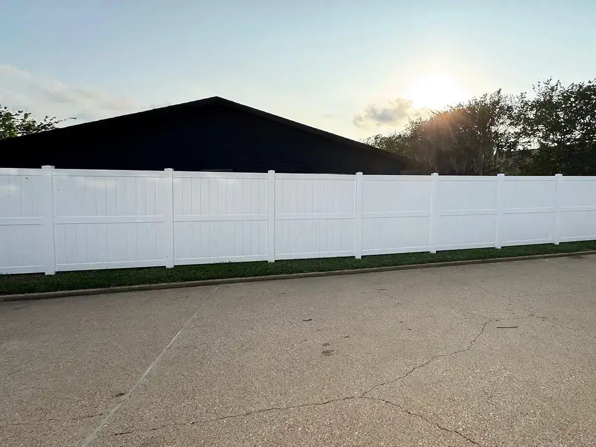 White vinyl privacy fence with post caps running along a commercial property