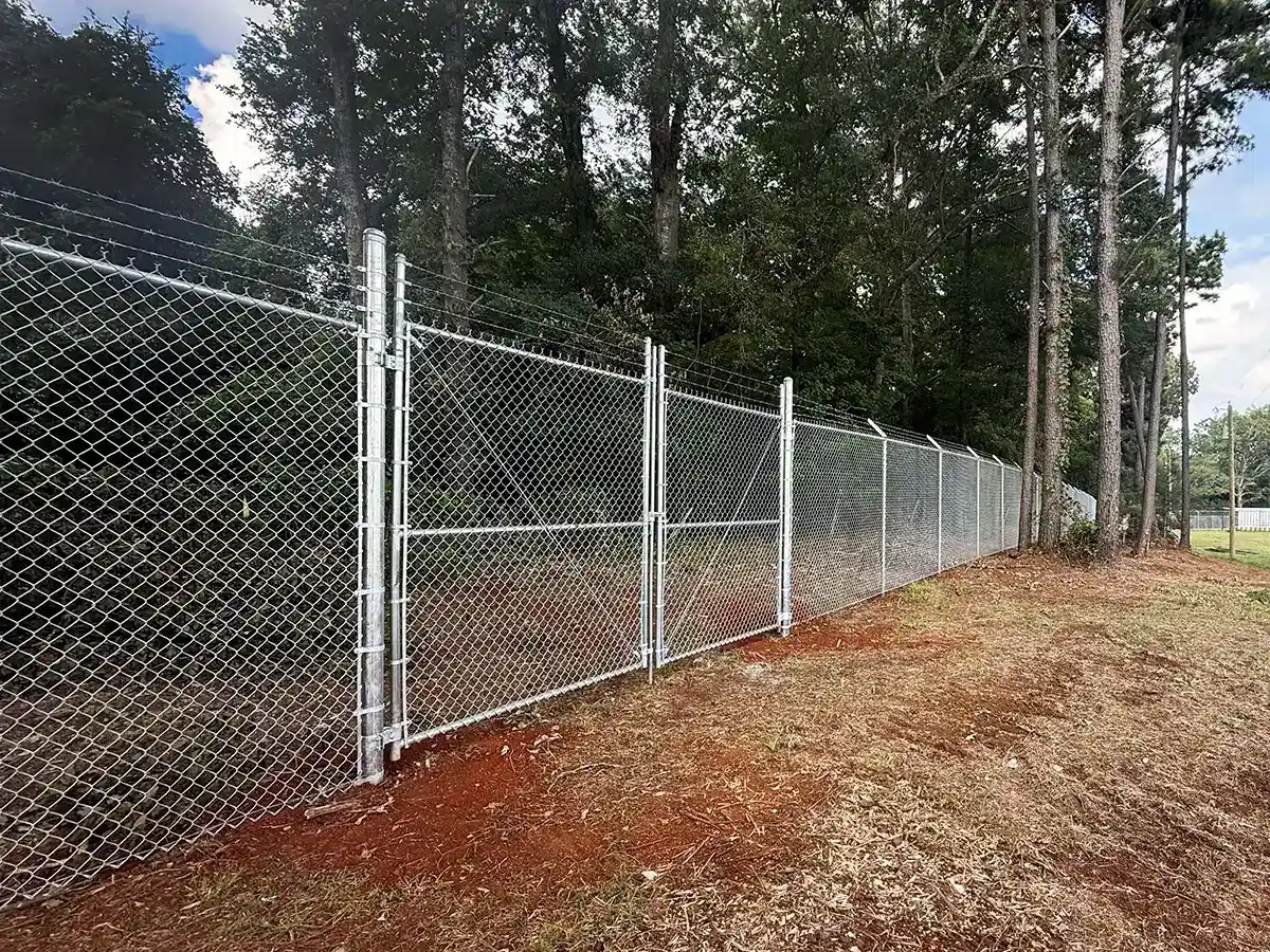 Chain link fence and double swing gate with barbed wire on top installed around a commercial area