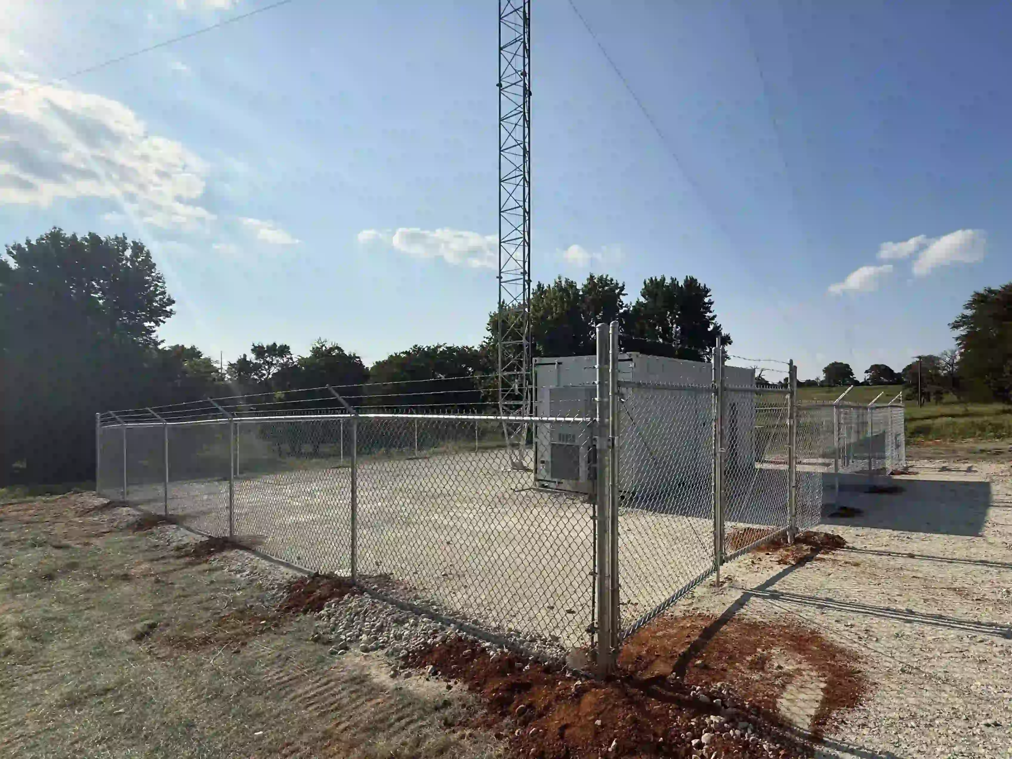 Galvanized chain link fence with barbed wire and a gate installed around a commercial area