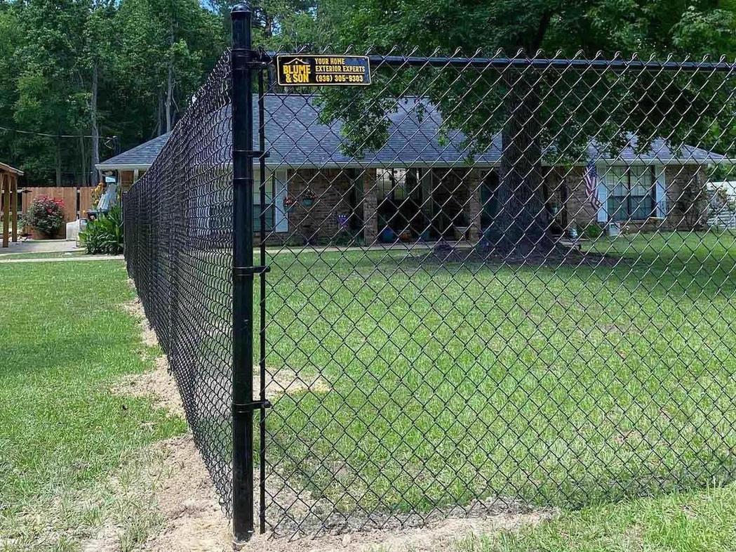 Black vinyl-coated chain link fence enclosing a landscaped backyard