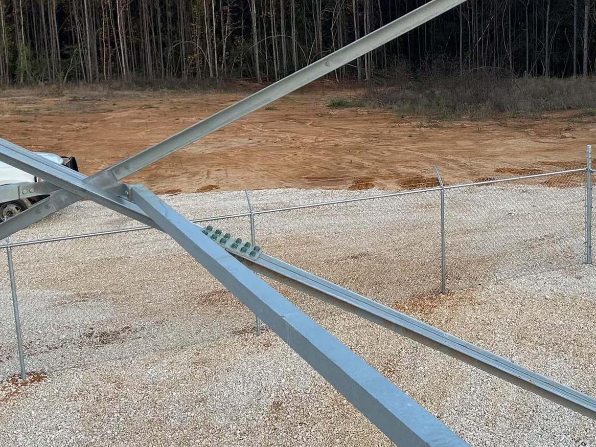Galvanized commercial chain link fence framework during a mid-installation on a gravel lot