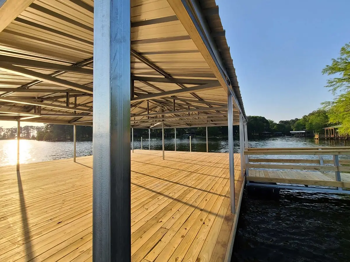 New boat dock featuring a light-colored wood deck and a metal roof structure over a lake