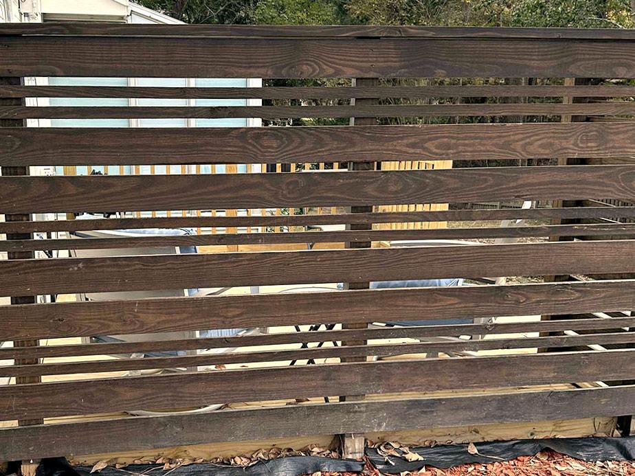 Dark stained wood horizontal slat fence with spaced boards