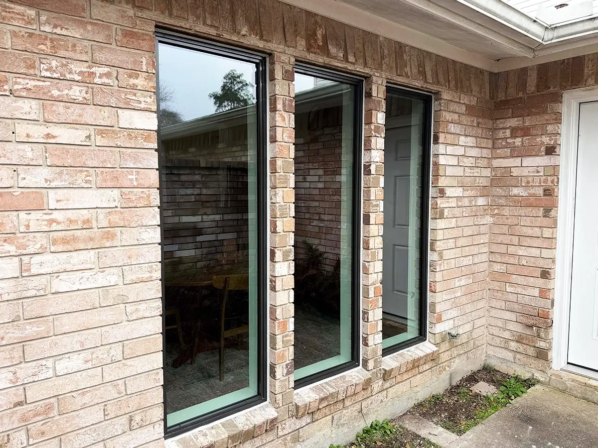 A series of tall, narrow casement windows installed in a brick-walled house
