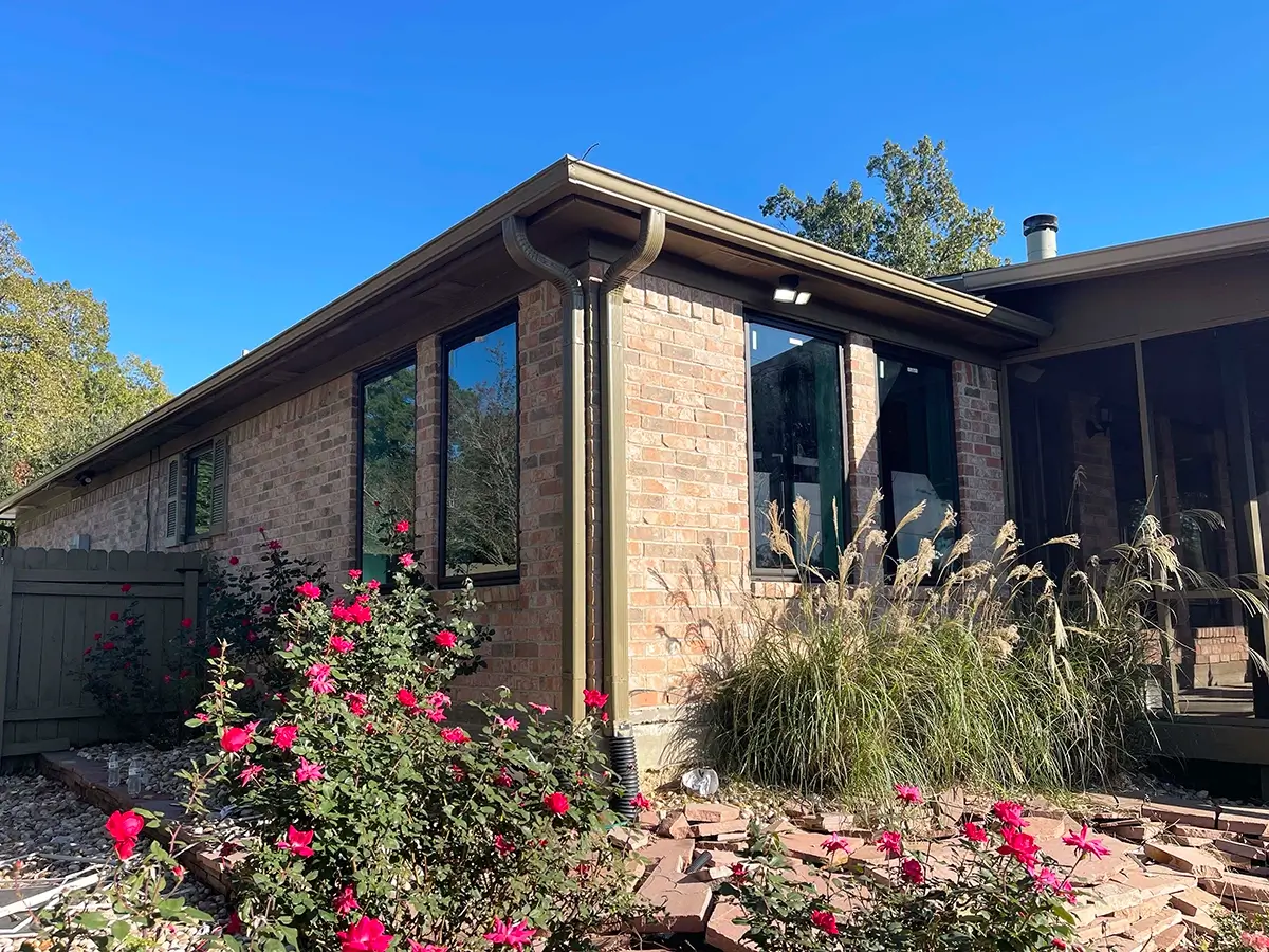 Exterior corner of a brick house featuring newly installed black aluminum windows